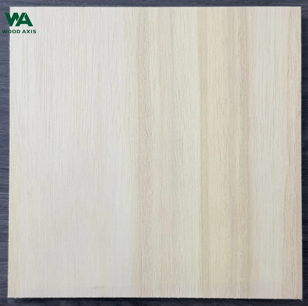 A high-resolution macro photograph of a rubberwood plywood face veneer, showing its characteristic pale cream to light straw color tone, straight grain lines, and small, evenly distributed open wood pores.